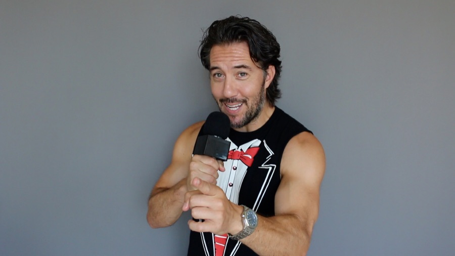 Max in an announcer / hosting tux print, holding a microphone