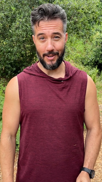 Max talking to camera outdoors in a maroon sleeveless hoodie